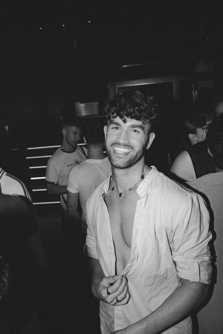 Chico sonriendo con camisa blanca abierta en YASS! Party Barcelona